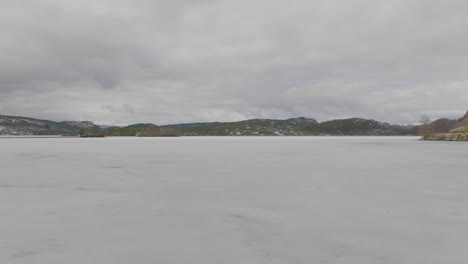 Flying-Over-Ice-covered-Lake-With-Overcast-Sky