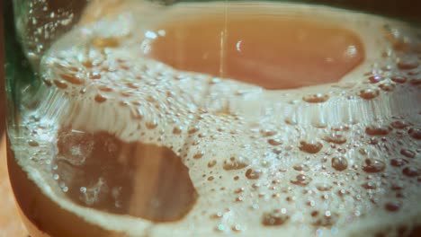 close up of pressed apple juice flowing into a glass with some foam