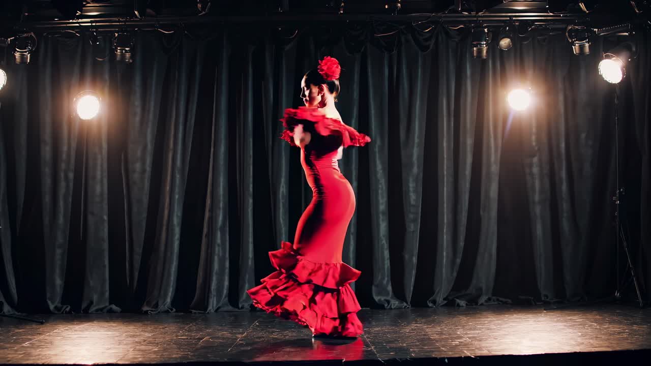 A dramatic, low-angle video captures a flamenco dancer in a vibrant red dress on stage