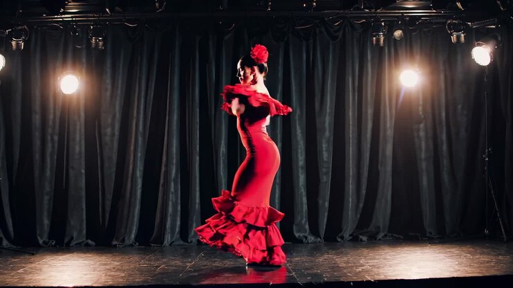 A dramatic, low-angle video captures a flamenco dancer in a vibrant red dress on stage