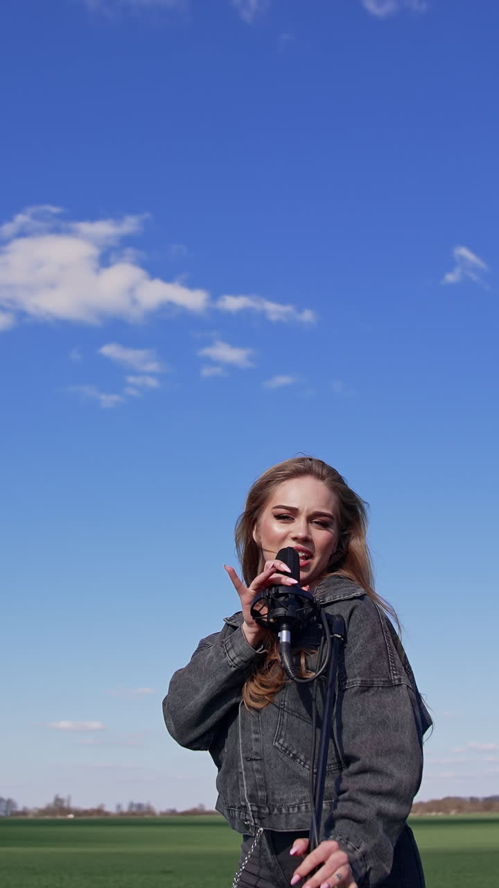 Girl singing with microphone on nature. Young woman singing with microphone on nature. Vertical video