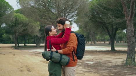 couple hugging autumn forest vertically. cute family embracing in nature park.