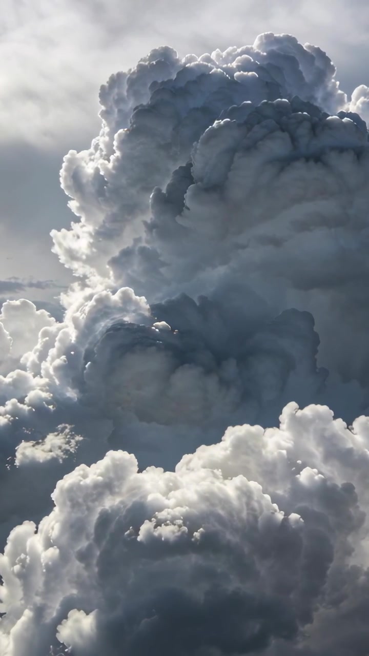 Video verticale: Nuvola alta che si sposta, reagendo alla luce solare che sfiora le creste, modellando il cielo aperto con una sbuffata.