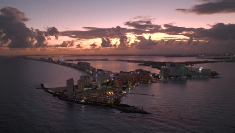 vista aérea frente a la bahía de punta cancún, puesta de sol nublada en quintana roo, méxico - ascendente, disparo de drones
