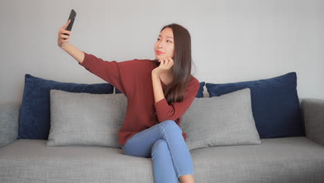 a young very attractive woman is sitting on a couch takes selfies from a number of different angles