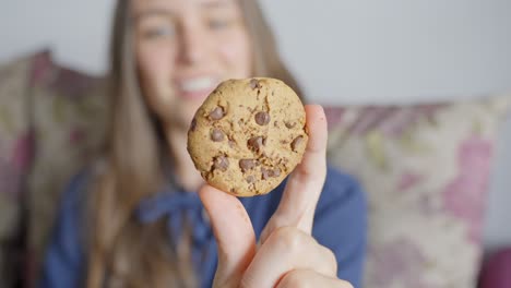 una mujer joven y alegre sostiene una deliciosa galleta de chocolate, vista frontal