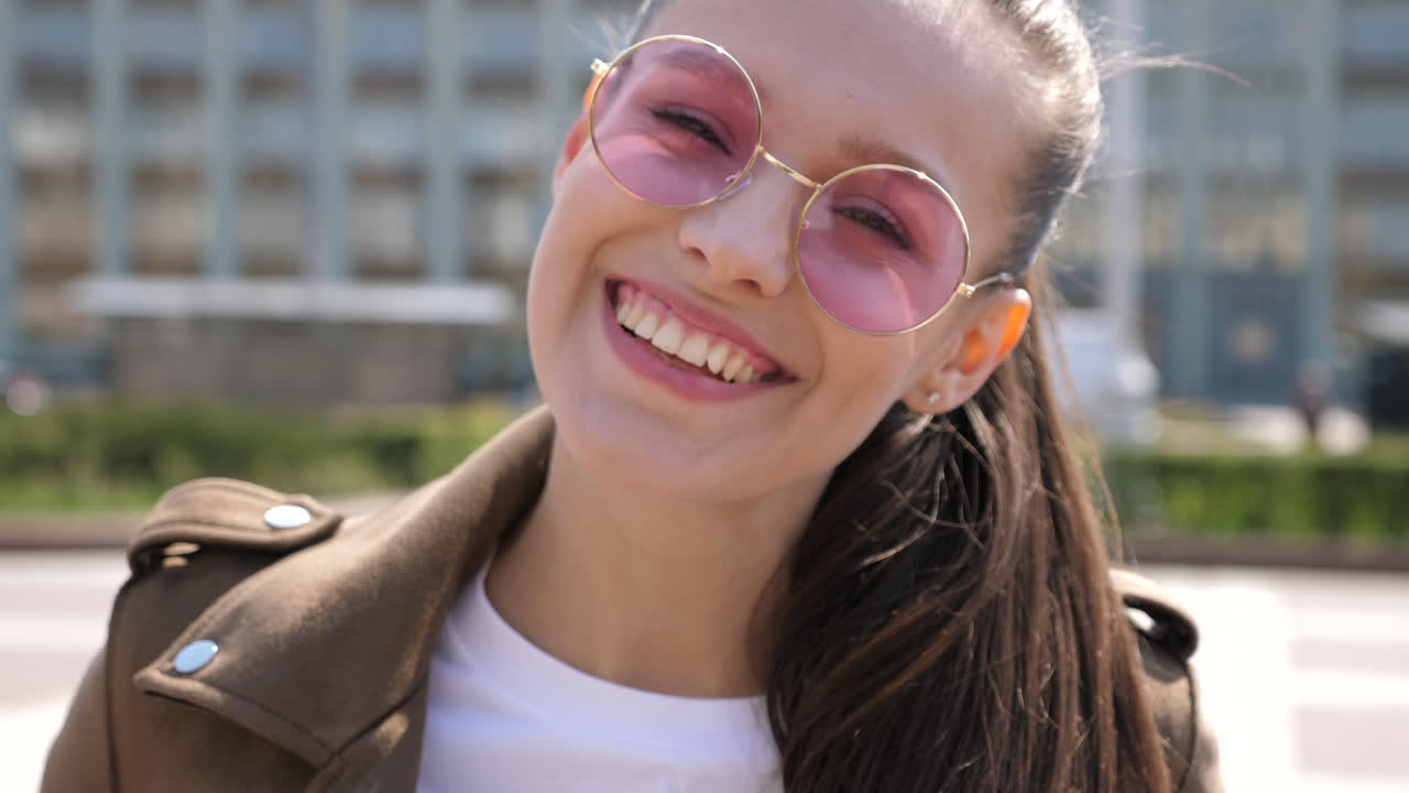 mujer sonriente con gafas de sol rosas