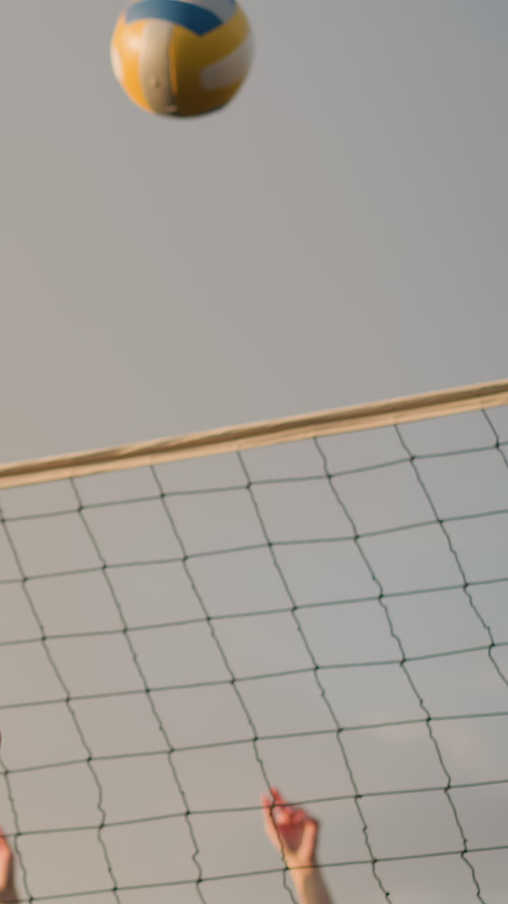 Primo piano di un giocatore di pallavolo che cerca di bloccare la palla sulla rete, con la luce del sole che crea un bagliore caldo; la ripresa da dietro cattura il movimento atletico concentrato, con cielo sfocato e luce naturale soffusa