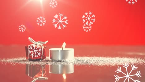 Animation-of-candle-and-present,-snow-falling-on-red-background
