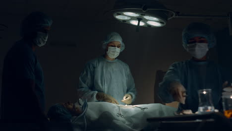 equipo médico realizando una cirugía en la habitación del hospital. cirujano pasando instrumentos.