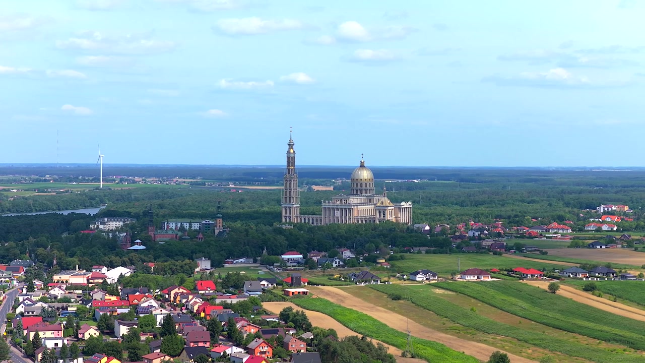 Naturskønt luftfoto i kredsløb af Vor Frue af Lichen-basilikaen, et stort katolsk pilgrimssted i Polen, omgivet af marker.