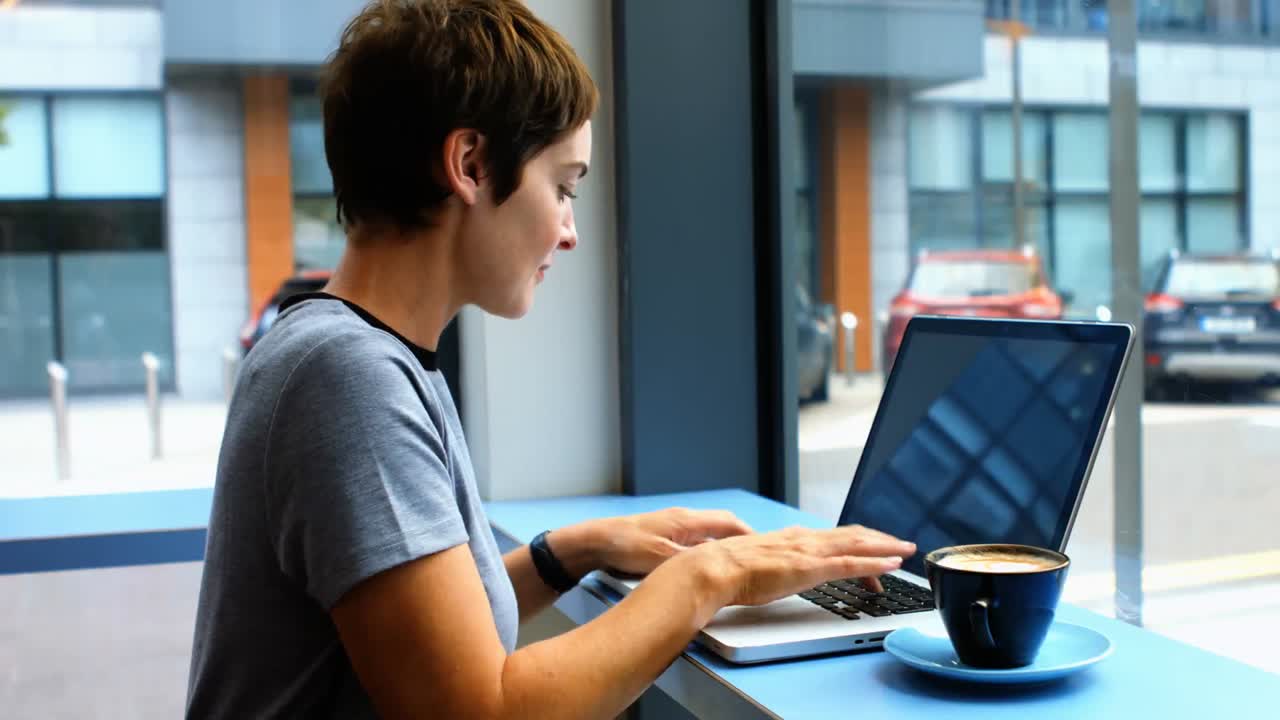 mujer de negocios tomando una taza de café mientras usa una computadora portátil