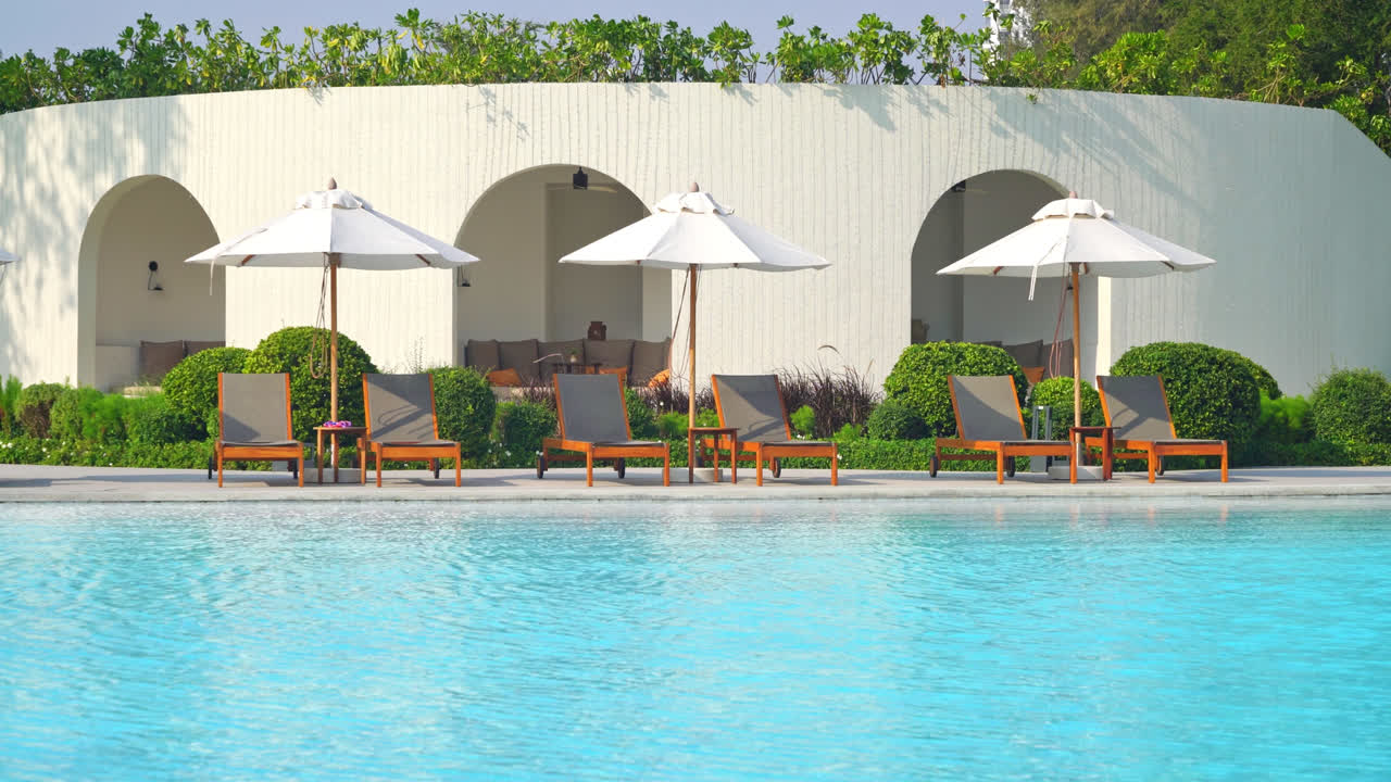 海の背景とスイミングプールの周りのベッドプール付き傘-休日と休暇のコンセプト