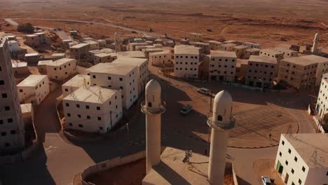 aerial shot of two mosques next to the main squere in an old empty city in the desert in palestine near gaza at sunset.