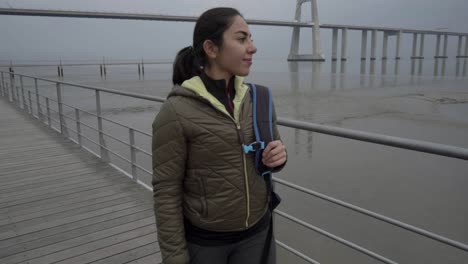 smiling brunette hindu woman walking on wooden pier