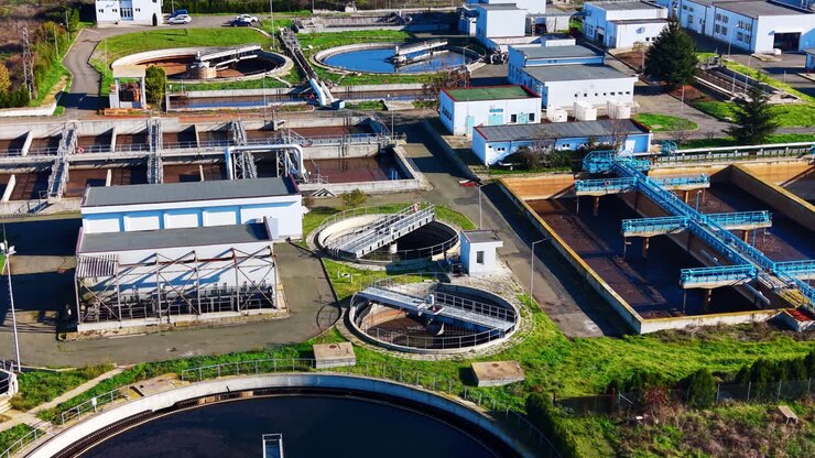 Detailed view of various industrial basins, pipes, and walkways within a modern sewage purification complex. Aerial shot of wastewater treatment tanks and pipes