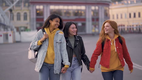 multi ethnic happy women walk together hand in hand outdoors