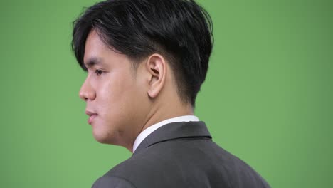 young handsome asian businessman against green background