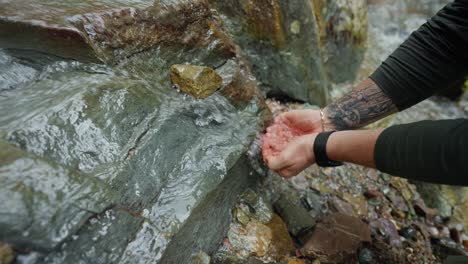 person drinking water from a mountain stream