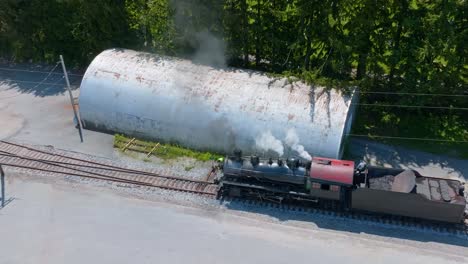 an aerial view of a vintage steam locomotive chugs along the railway near a switch as the fireman switches the track, so the engine can switch tracks.