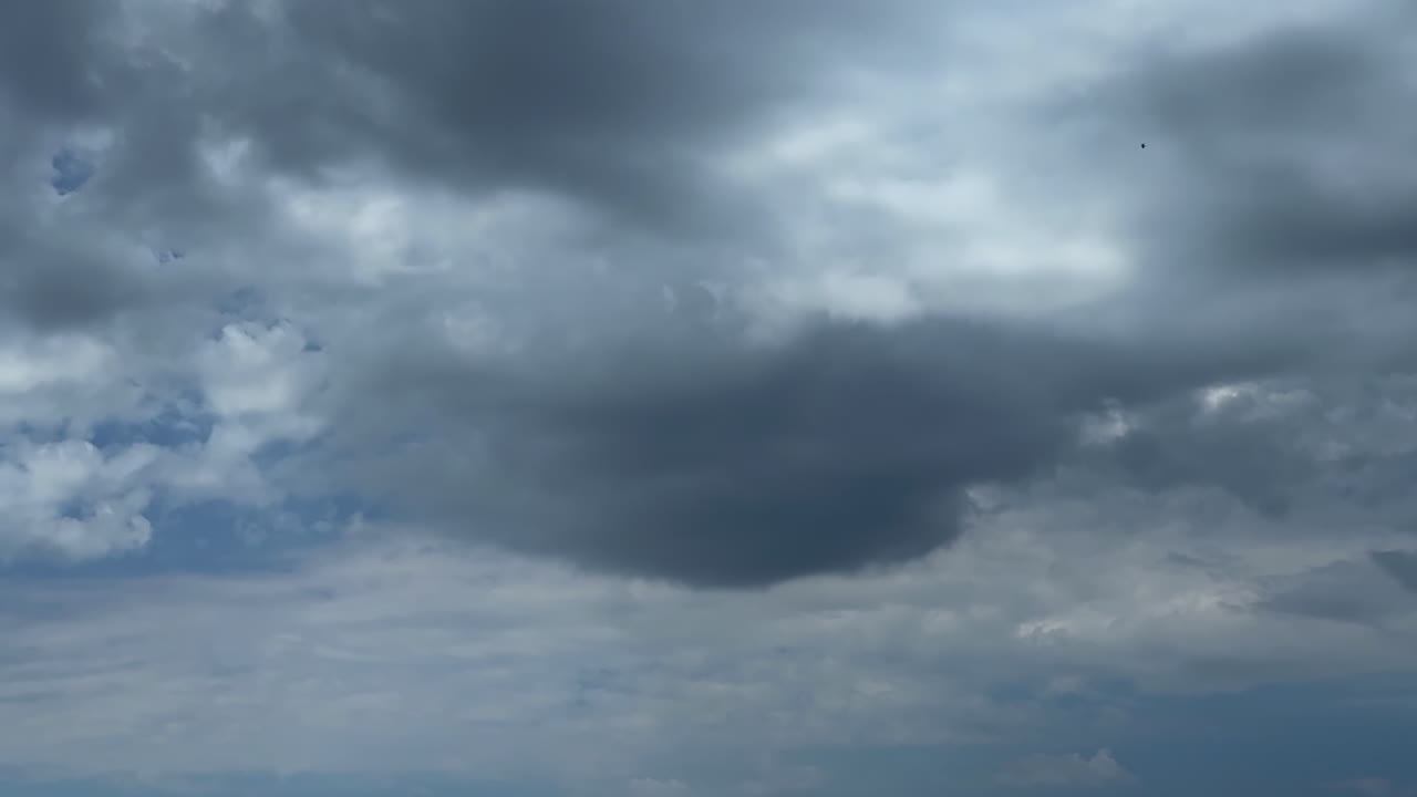 Grey clouds float in the sky. Low angle view at the dramatic cloudscape covering the sky
