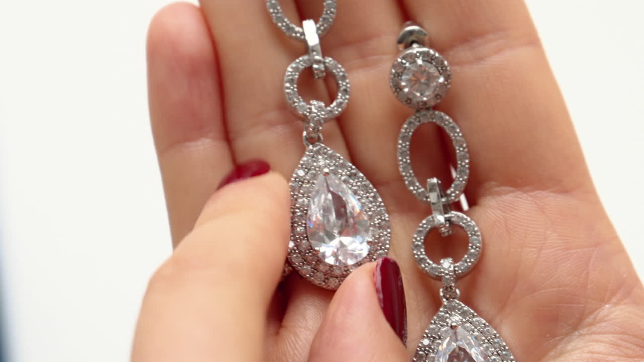 Woman hands playing with pear cubic zirconia drop earrings