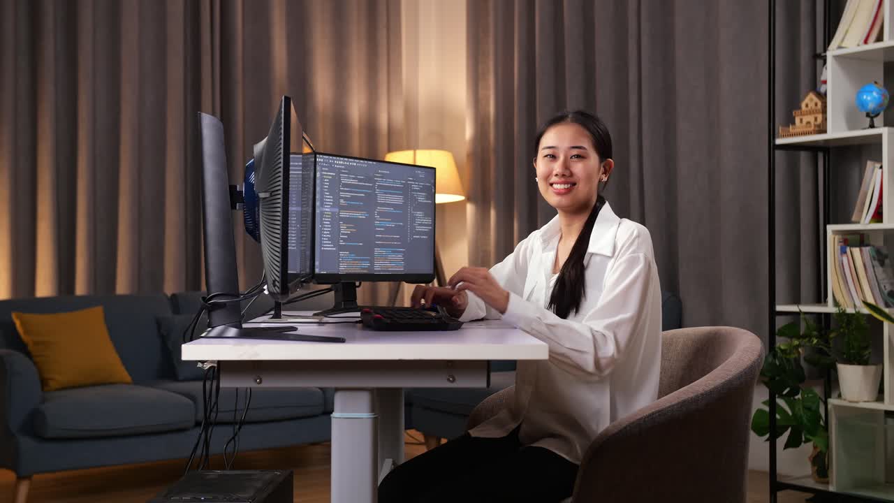 아시아 여성 프로그래머가 미소 짓고 팔을 는 동안 소프트웨어 엔지니어가 집에서 데스크 컴퓨터에서 앱, 프로그램, 비디오 게임을 개발합니다.