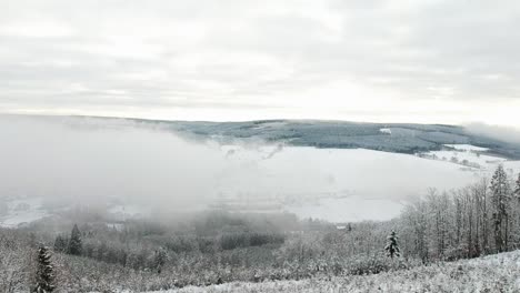 rising aerial overlooking snowy valley landscape hills pine trees forest day