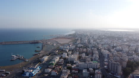 Aerial-flying-backwards-at-Larnaca-coastline-on-sunny-day,-Cyprus