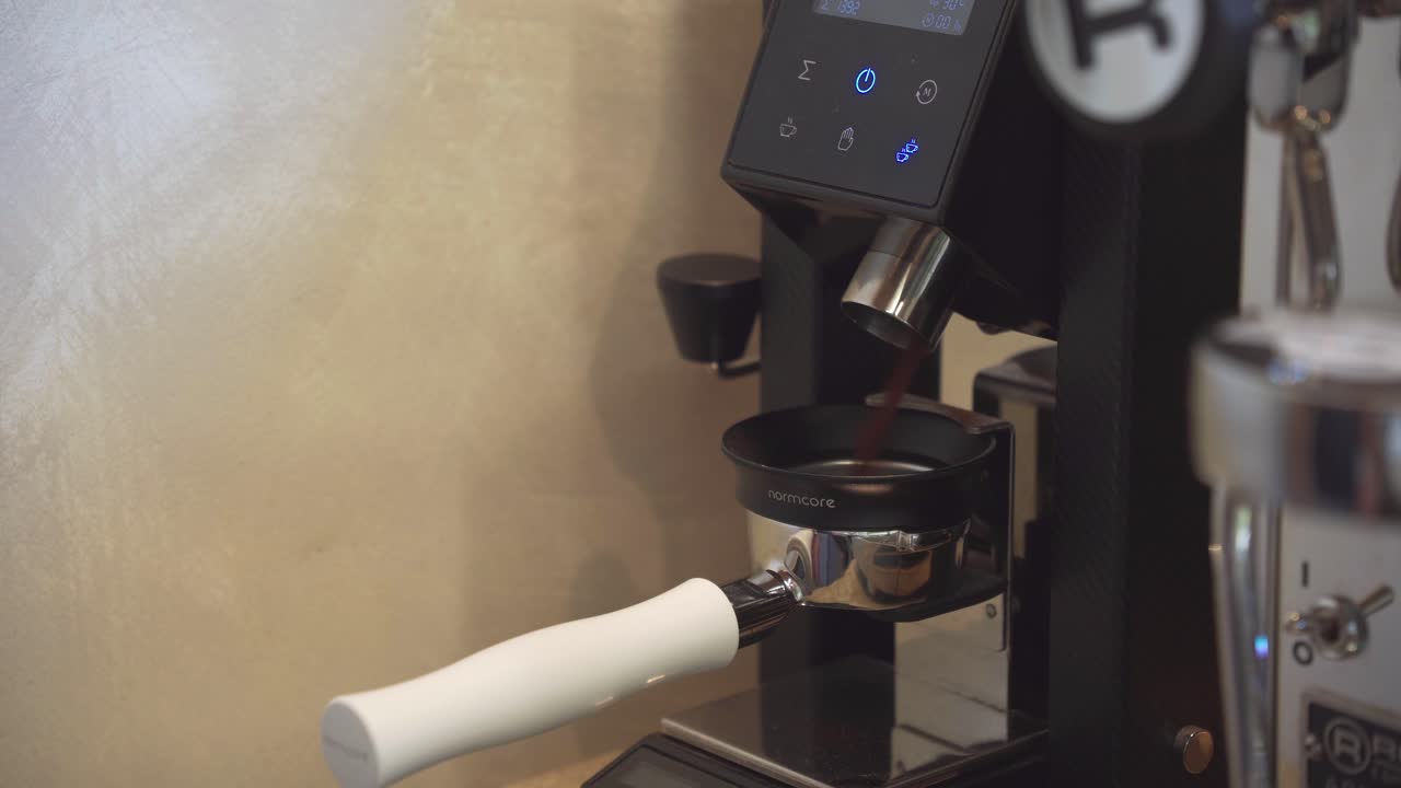barista presiona el botón de la pantalla táctil en el molinillo electrónico de granos de café para comenzar