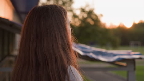 sad young woman looks at sunset near building. evening walk and personal depression due to loneliness. depressive state in calm atmosphere of summer day