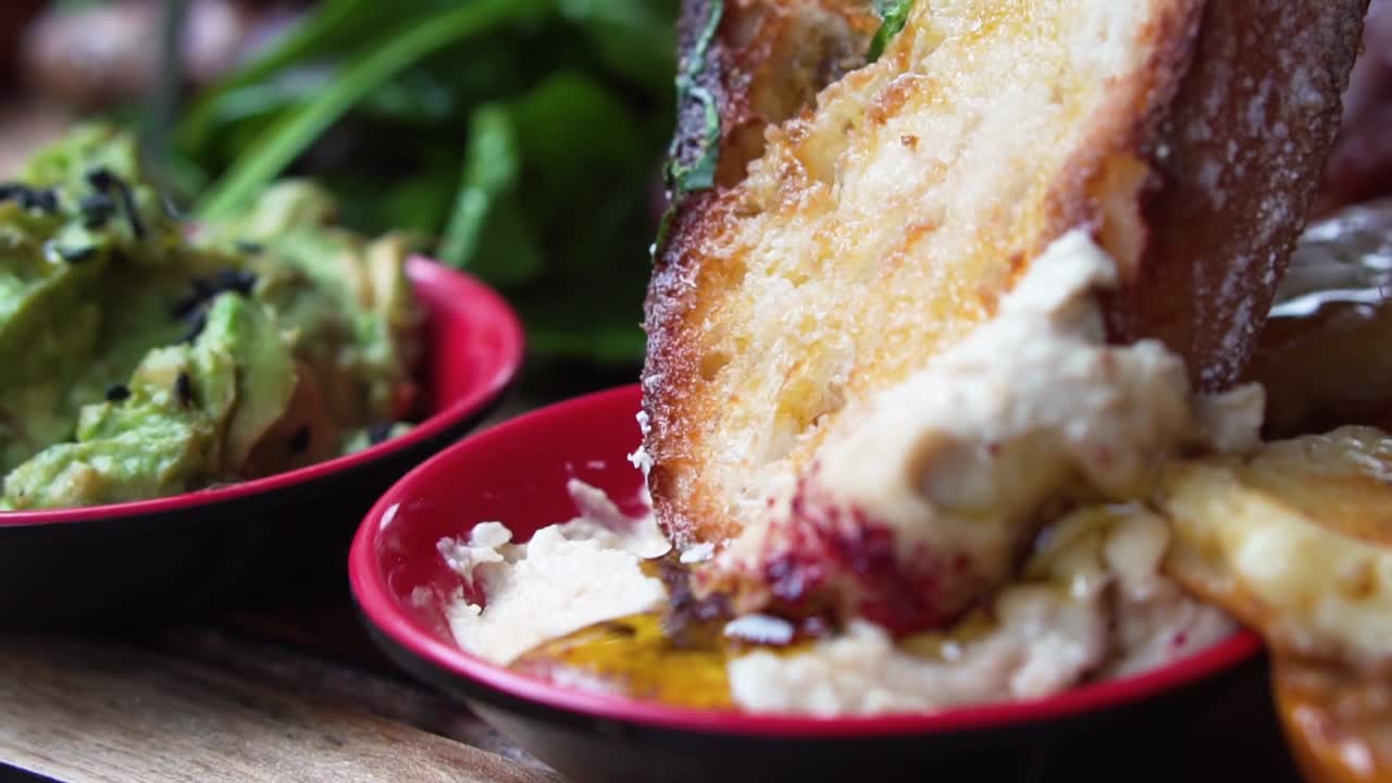 Dipping rustic bread into hummus