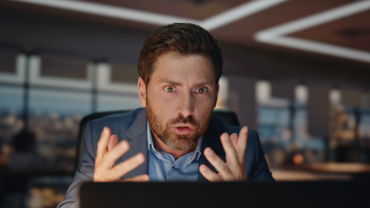 un hombre de negocios loco discutiendo en línea, una noche de trabajo cercano, un hombre enojado llamando por video.