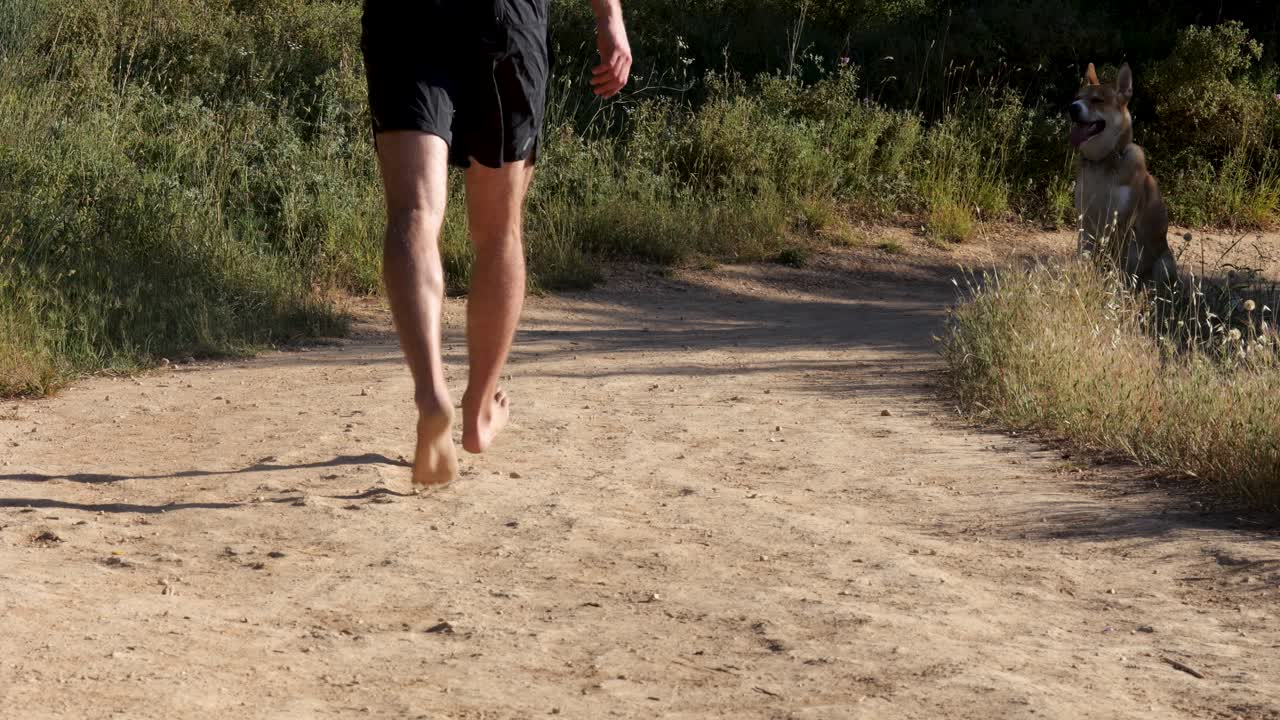 Toma de una persona corriendo por la mañana en un sendero forestal urbano con su perro.