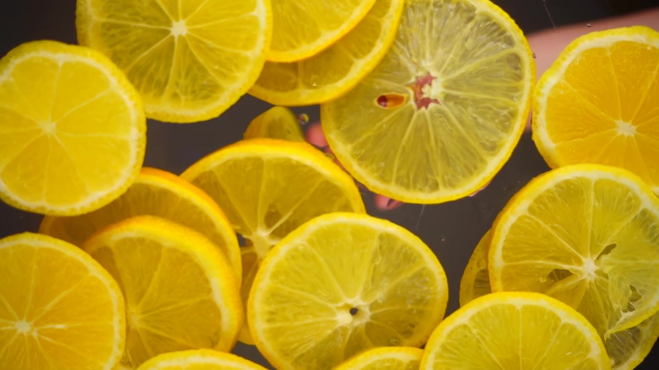 Fette di limoni cadono su una superficie trasparente. Vista dal basso.