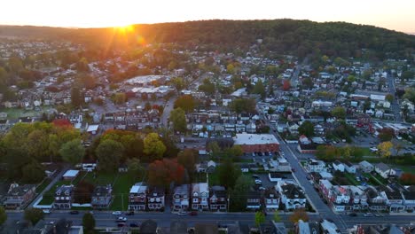 golden sunrise over a quaint town with autumn trees and a backdrop of rolling hills