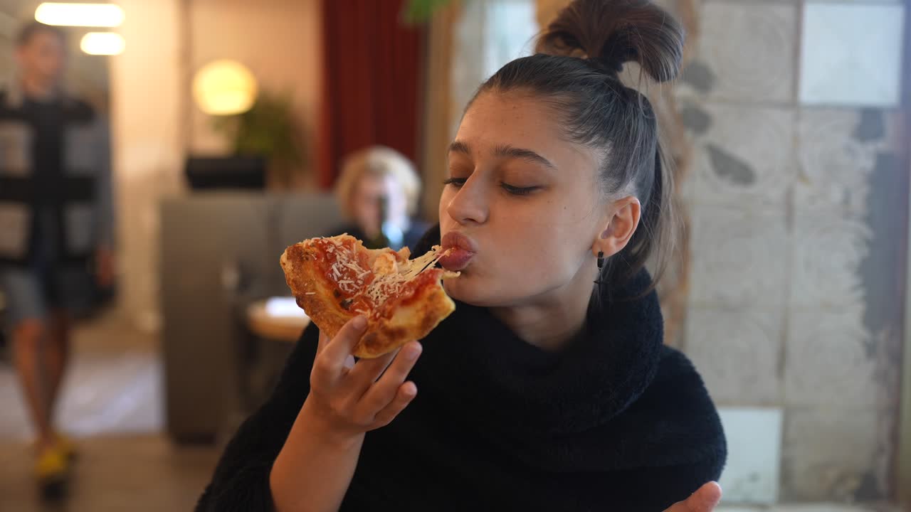 un adolescente comiendo pizza en un restaurante