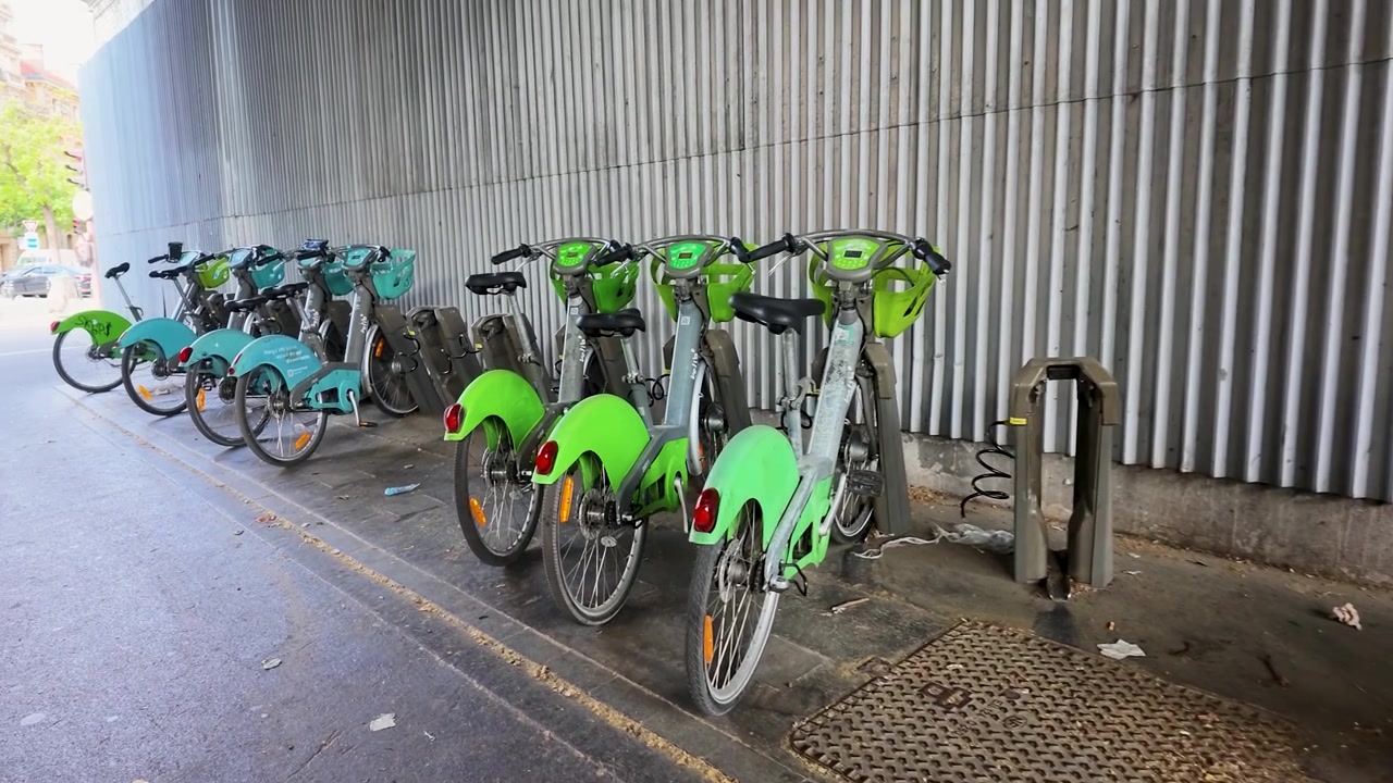 Bicicletas de aluguel verdes estacionadas em uma estação urbana sob um viaduto em Paris