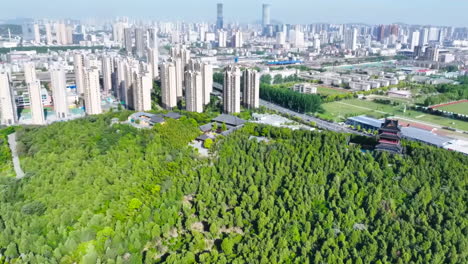 aerial view of a city blending modern high-rises, lush forests, and traditional architecture