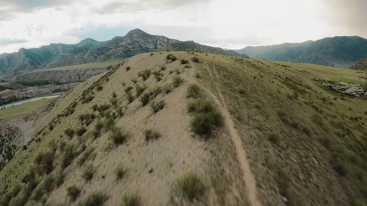 Dirt tracks on mountain ridge in river valley fpv drone. Trails embody sense of adventure beckoning explorers to embrace challenge. Highland terrain