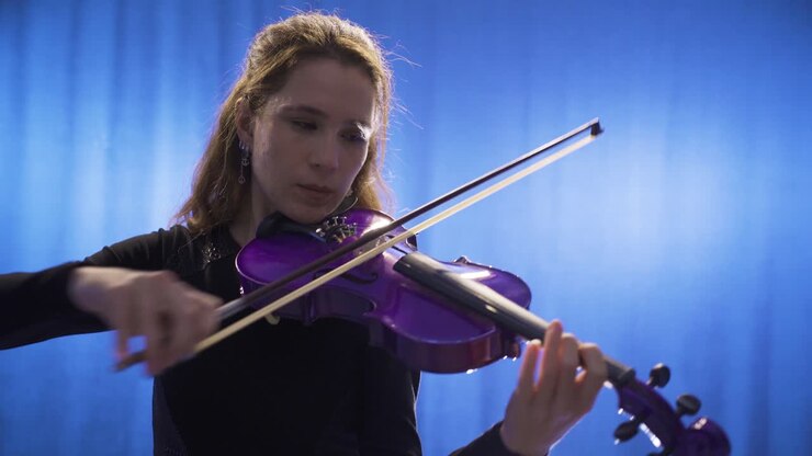 Primo piano di giovane violinista sul palco e del suo violino