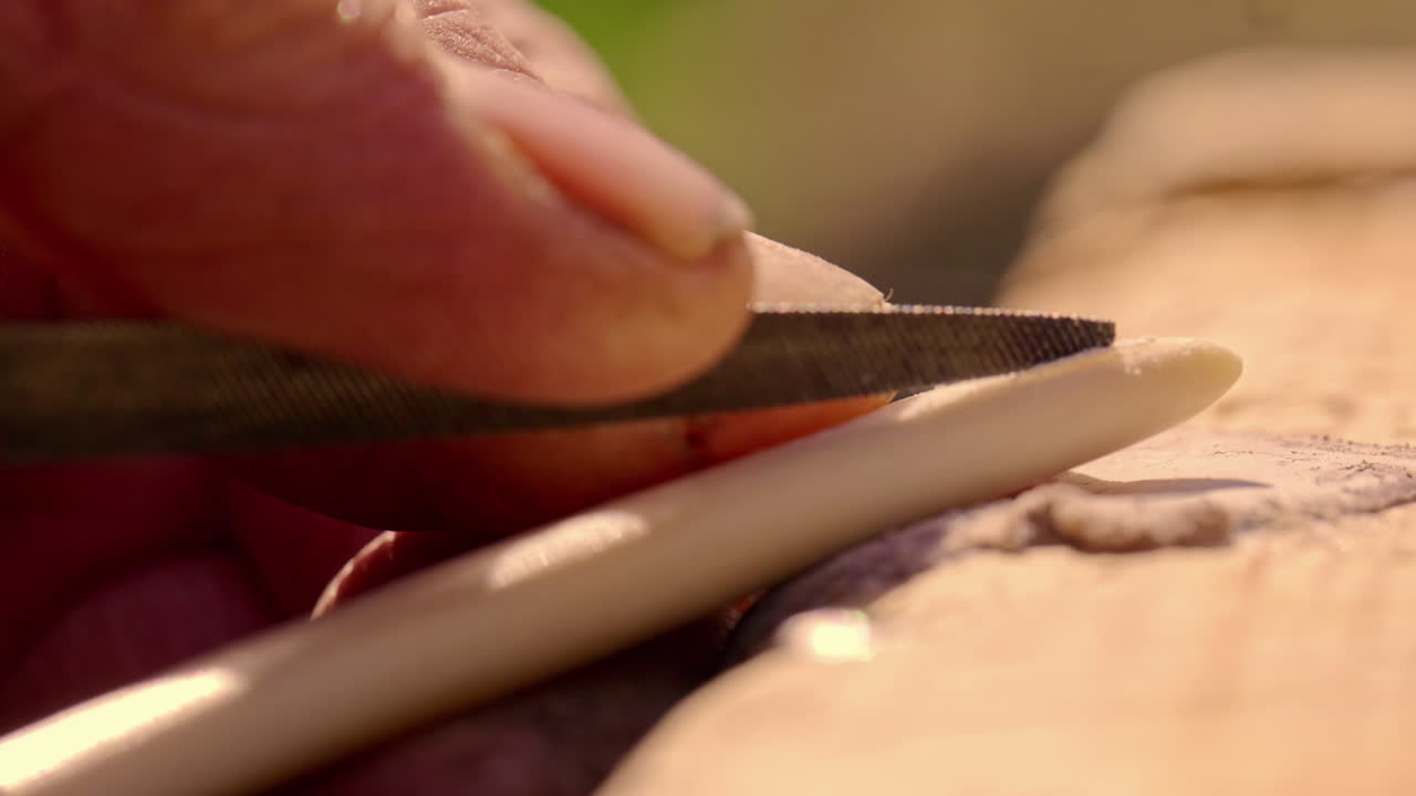 Extreme close-up craftsman filing ivory sharp utensil, Viking Experience