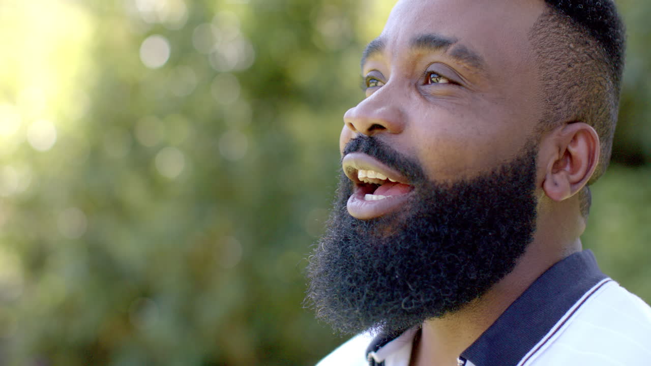 Smiling african american man with beard enjoying outdoor nature, happy and relaxed, copy space