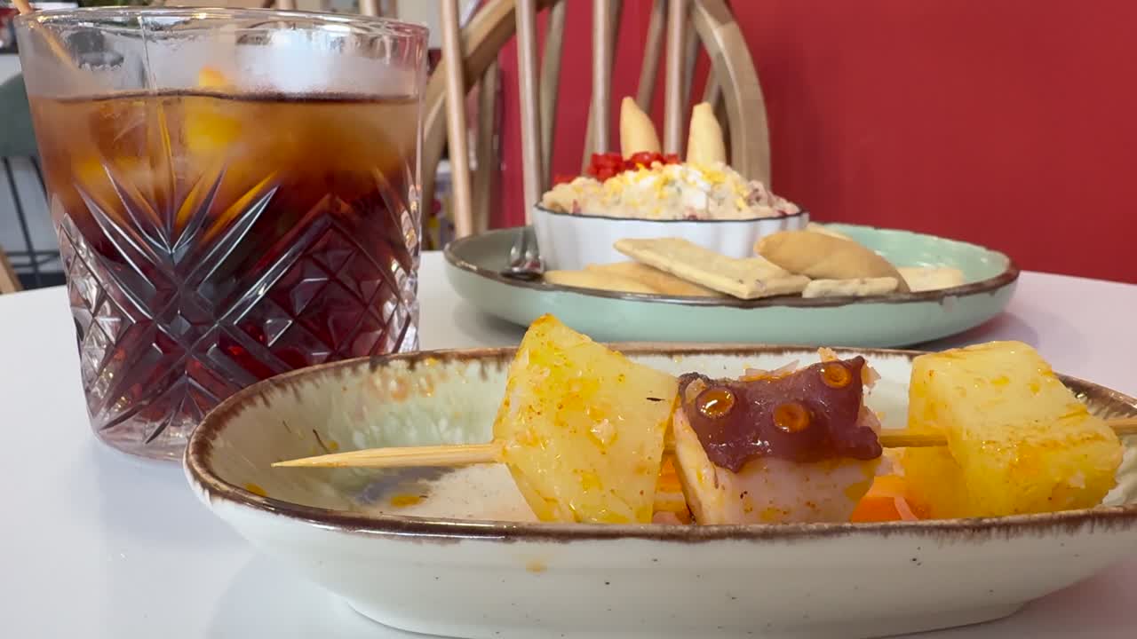 Vista de cerca de la mano de un hombre caucásico tomando un pincho de pulpo y patatas en un bar tradicional español.
