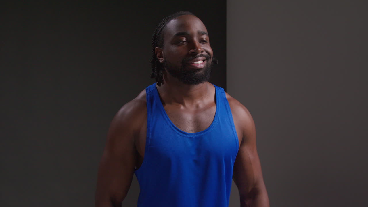 retrato de estudio de un atleta masculino con chaleco de entrenamiento deportivo o ejercicio en el gimnasio contra un fondo negro
