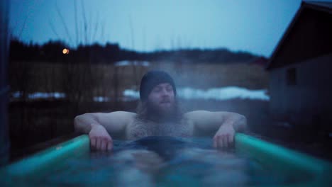 caucasian man relaxing on diy wood-powered hot tub