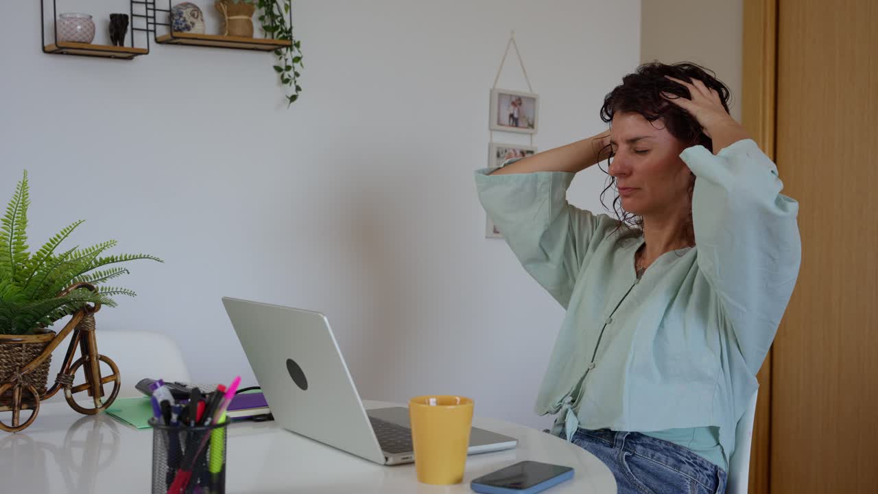 Kvinde lider af hovedpine, mens hun arbejder på bærbar computer derhjemme