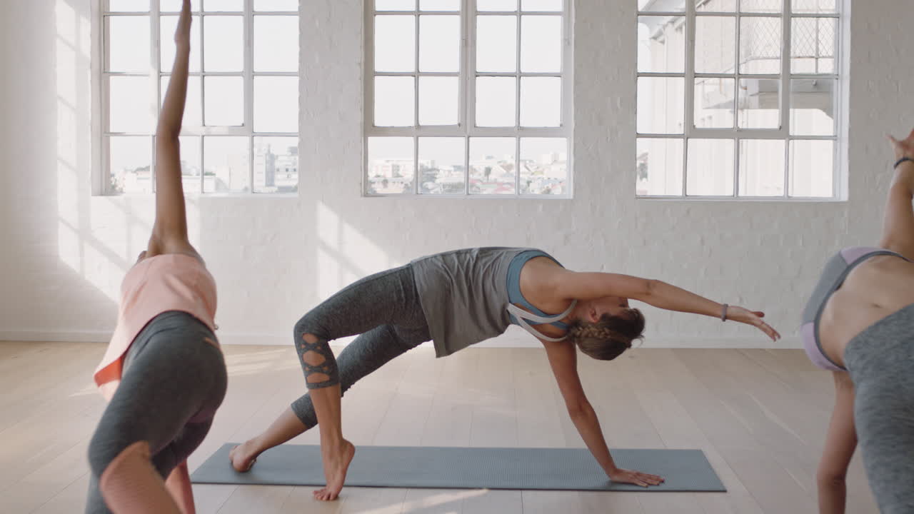 yoga-kursleiter leitet gruppenmeditation und unterrichtet gesunde frauen in balance-posen, die das training im fitnessstudio genießen und die körperhaltung üben
