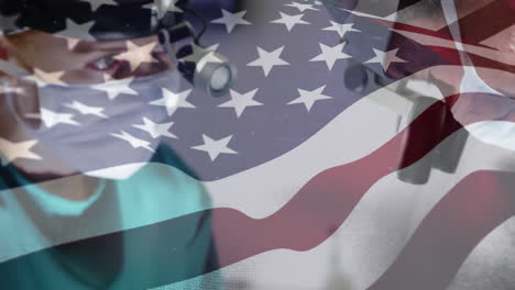 animation of flag of usa waving over surgeons in operating theatre