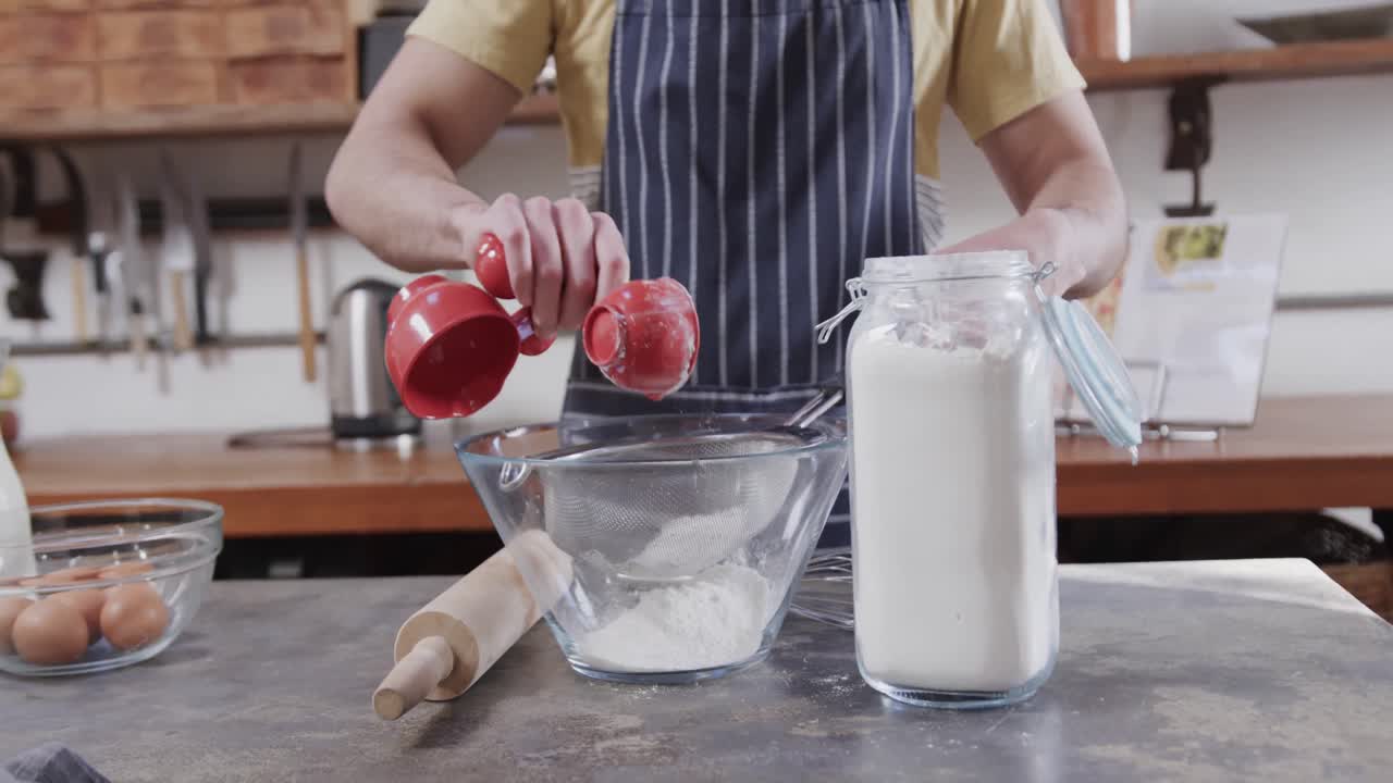 sección media de un hombre caucásico preparando masa de pan en la cocina, cámara lenta